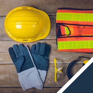 Yellow hard hat, safety vest, gloves, goggles, and earmuffs arranged on a wooden surface.