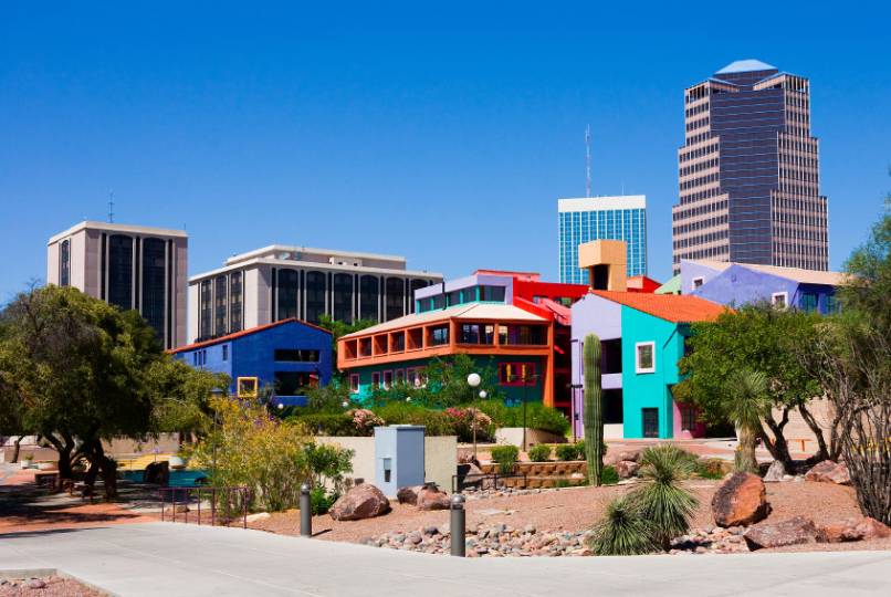Colorful buildings surrounded by trees, with tall modern skyscrapers in the background under a clear blue sky. Colorful buildings surrounded by trees, with tall modern skyscrapers in the background under a clear blue sky.