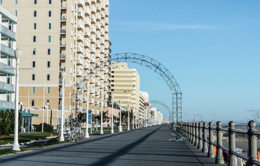 A beachfront promenade lined with tall buildings and metal archways on a clear day. A beachfront promenade lined with tall buildings and metal archways on a clear day.